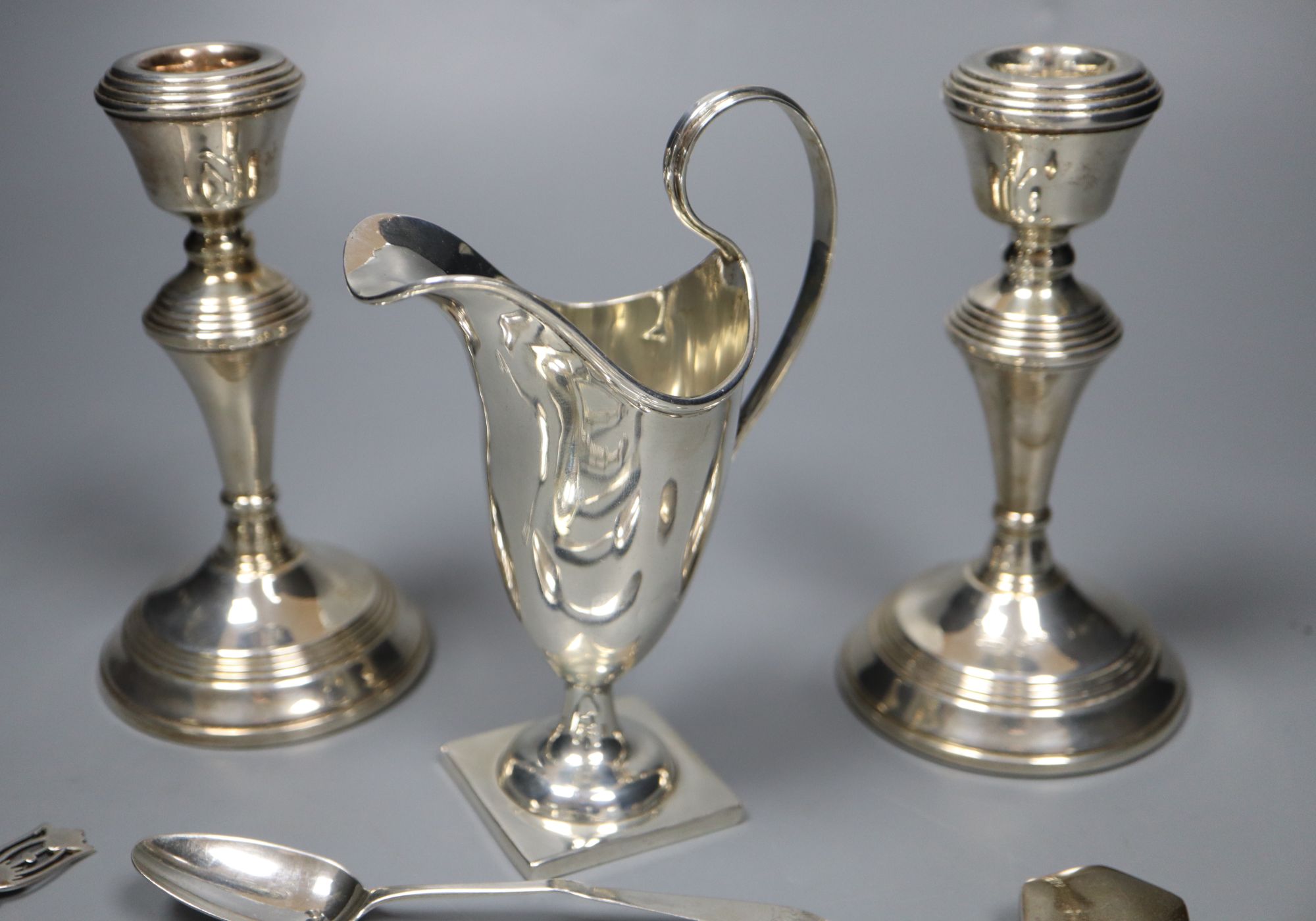 A quantity of small silver to include a pair of candlesticks, sauce ladle, cream jug etc and a silver plated rattle,